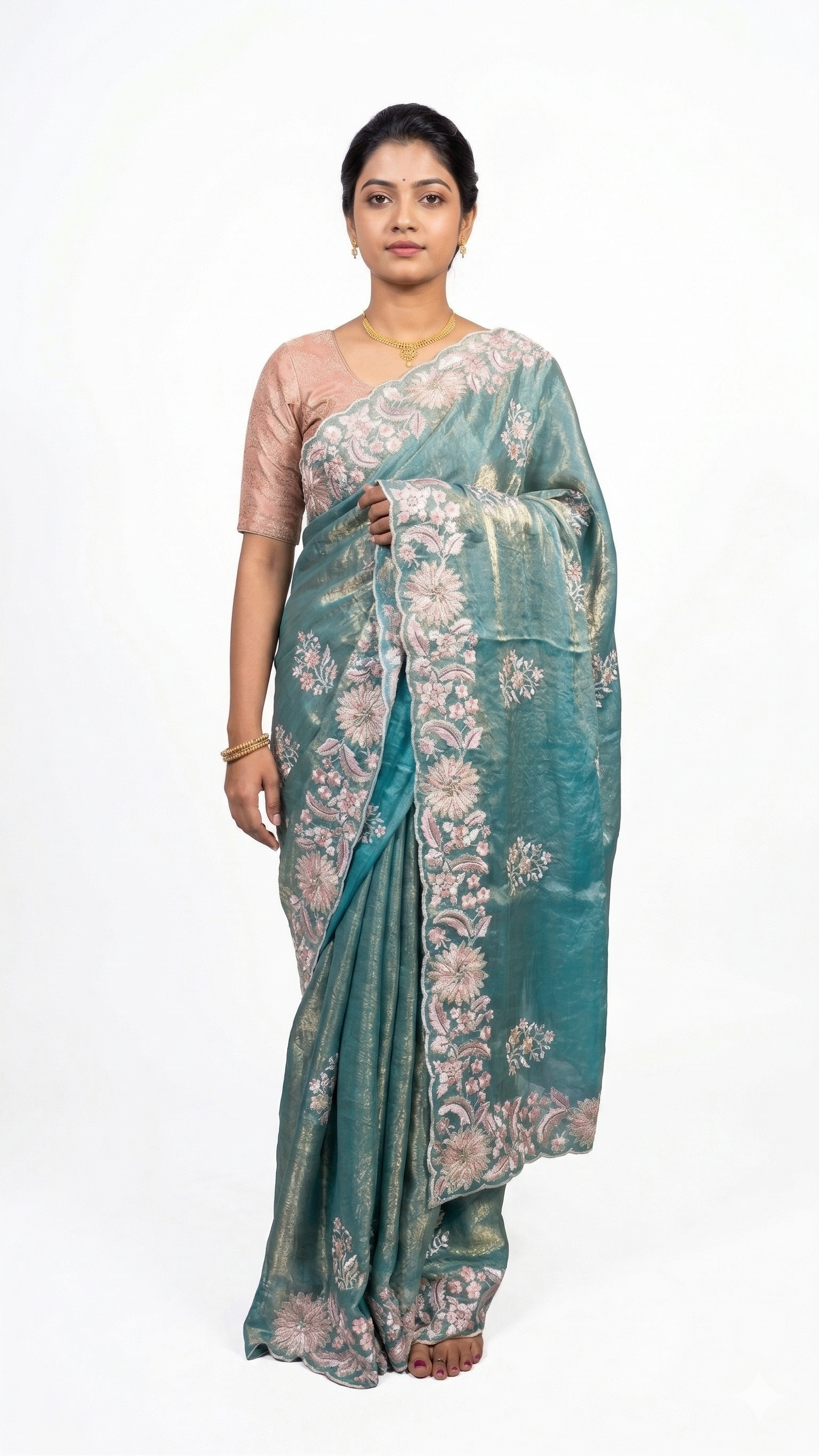 Woman wearing a teal saree with floral patterns on a white background