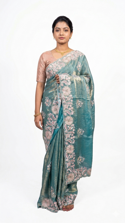 Woman wearing a teal saree with floral patterns on a white background